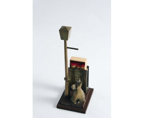AN EARLY 20TH CENTURY BRASS MATCH BOX HOLDER in the form of a small dog by a wall & lamp post entitled "RENDEZVOUS";  7.3"  (