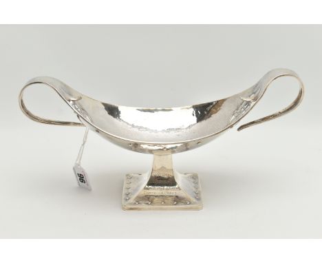A GEORGE V PLANISHED SILVER ARTS AND CRAFTS TWIN HANDLED OVAL PEDESTAL BOWL, the elongated scroll handles terminating in a cu