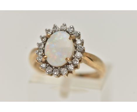 A 9CT GOLD OPAL AND DIAMOND CLUSTER RING, oval opal prong set with a surround of eighteen round brilliant cut diamonds, leadi