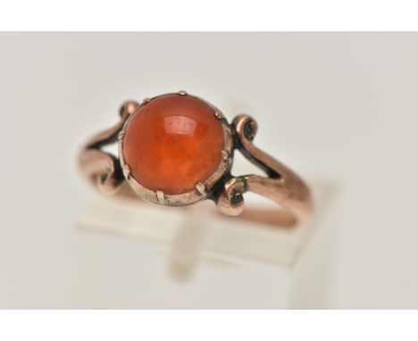 A ROSE METAL CARNELIAN RING, set with a circular cut carnelian cabochon, claw set, bifurcated scroll shoulders leading onto a