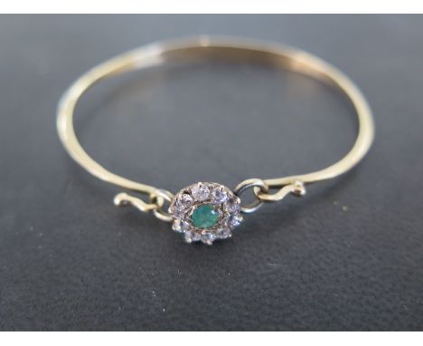 A hallmarked 9ct yellow gold diamond and emerald cluster bangle - cluster measures approx 10mm wide - approx weight 5 grams -