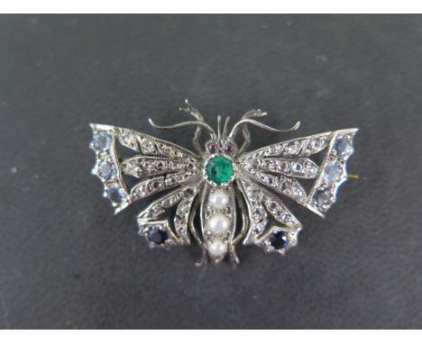 An early 1900s yellow gold inset brooch in the form of a moth set with an emerald above a three pearl body with diamonds to t