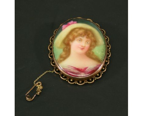AN EDWARDIAN 9CT GOLD MOUNTED & HAND-PAINTED PORCELAIN BROOCH of oval form decorated with a portrait of a young woman, signed