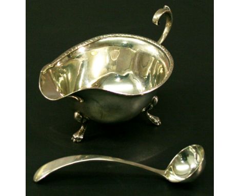 A GEORGE V SILVER SAUCE BOAT of typical ovoid form with moulded rim, scroll handle and three cabriole type legs, marks for Bi