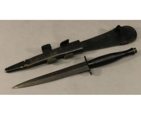 A POST WAR COMMANDO DAGGER in black riveted scabbard. CONDITION:  Handle, guard and blade are loose but overall good.
