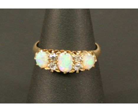 AN 18CT GOLD OPAL AND DIAMOND RING with three oval opal cabochones interspersed by small rose-cut diamonds, the shank marked 