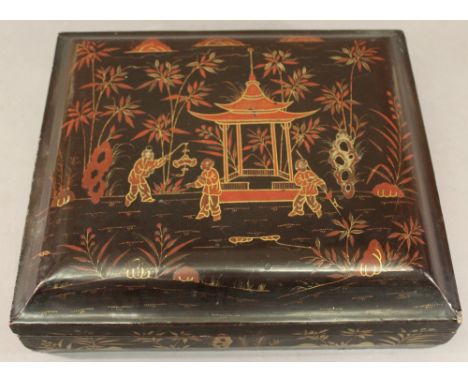 A 19TH CENTURY CHINESE LACQUERED GAMES BOX of rectangular form, having a lift-off top lacquered with a pagoda and figures and
