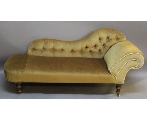 A VICTORIAN CHAISE LONGUE having a shaped and deep-buttoned back, scrolled arm and sprung seat, raised on turned legs with ce