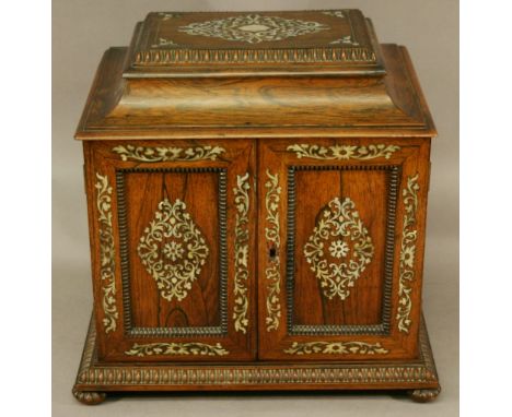 A 19TH CENTURY MOTHER-OF-PEARL INLAID ROSEWOOD JEWELLERY CABINET having a swept and moulded top, two panelled doors with four