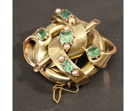 A VICTORIAN YELLOW METAL EMERALD AND PEARL BROOCH of entwined scroll, ring and rod form with inset emerald-cut emeralds and s