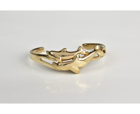 A 9ct gold dolphin bangle, of torque form with two moulded dolphins to the front.. 