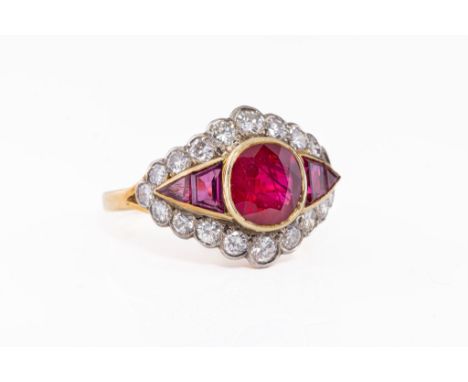 An 18ct yellow gold, ruby and diamond cluster ring, the central oval cut ruby, approx. 7 x 6mm., flanked by smaller trapezoid