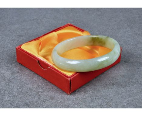 A Chinese carved celadon jade bangle, late 20th century, with spinach jade inclusions, internal diameter 6.5cm.. 