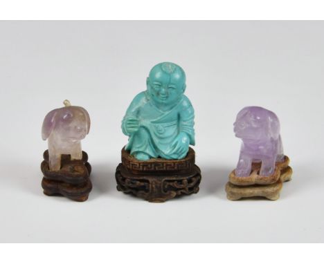 A miniature Chinese carved turquoise figure, sitting upon a carved hardwood stand, 2 ¼in. (5.8cm.) high, together with two mi