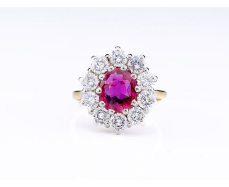 An 18ct gold, ruby and diamond cluster ring, the oval-cut ruby within a surround of brilliant-cut diamonds, to an 18ct yellow