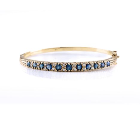 A 9ct gold, sapphire and diamond bangle, set to the front with an alternating row of round-cut sapphires and duos of brillian