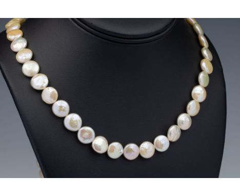 A button pearl necklace, with 10-12mm. diameter pearls and 18ct brushed gold pierced globe clasp, 31in. (79cm.) long.. 