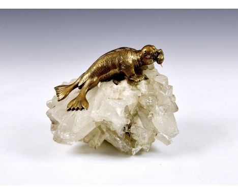 An unusual walrus on iceberg desk weight, the brass walrus model with glass eyes, mounted on a block of quartz as an iceberg,