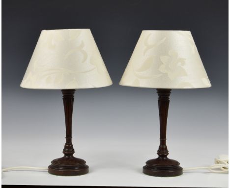 A pair of small mahogany table lamps of reeded column form, raised on stepped circular base, the tapering column terminating 