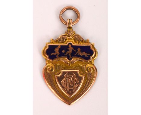 An Edwardian 9ct gold and enamelled footballing medallion of shield form, the front with raised panel engraved with initials 