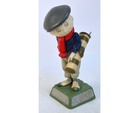 A reproduction Dunlop Caddie figure carrying a golf bag with three clubs, inscribed “We play Dunlop" to the base (af). CONDIT
