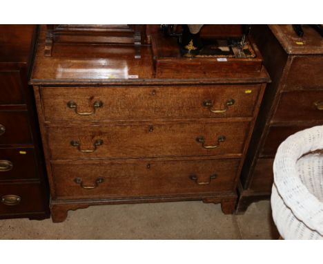 An antique oak chest of three drawers raised on bracket supports 