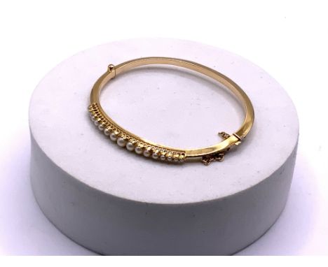 A gold bangle tested 14ct ( minimum) set with graduating seed pearls. Approximately 7.3g, (A).