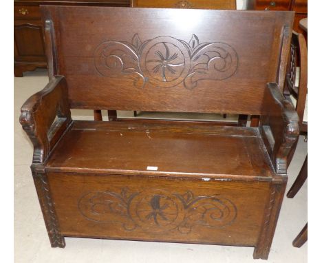 A reproduction oak monk's bench with carved decoration
