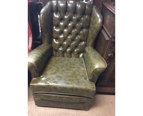 A green leather button back open armchair.