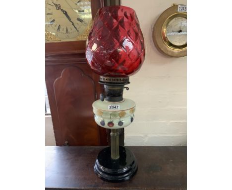 A late Victorian painted oil lamp and cranberry glass shade 58cm.