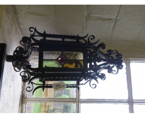 A stained glass and wrought iron lantern, possibly Morroccan, with scrolling decoration, 44cm high