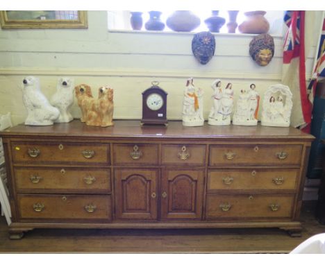 A George III oak and mahogany crossbanded dresser base, with two short central drawers above two panelled doors flanked by th