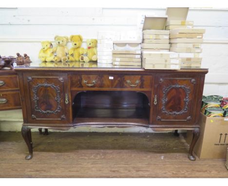 A 1920s mahogany sideboard by Maple & Co, the central drawer and open shelf flanked by foliate scroll applied doors on accant