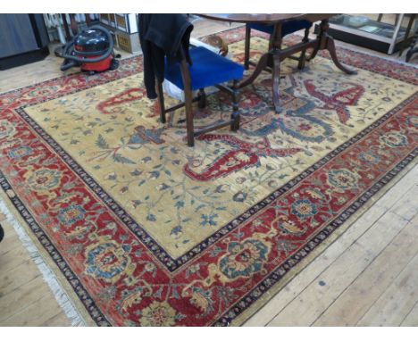 An Afghan carpet, the red and blue medallion on a sand field with floral scrolls within a red palmette border, signed, 367cm 