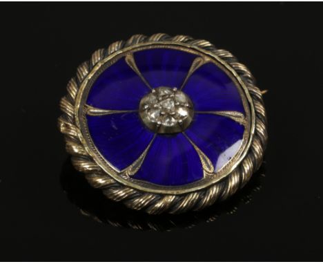 A gold (tested to 18ct) circular brooch set with blue enamel and old European cut diamonds bordered with ornate rose twist de