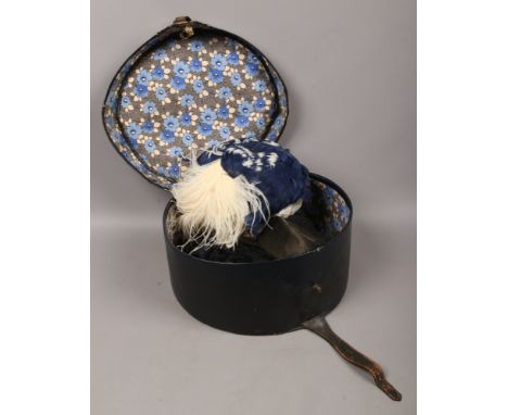 A vintage hat box with three ladies feather and veiled hats.
