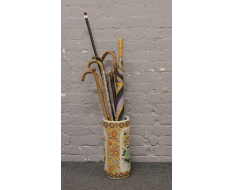 A floral decorated ceramic stick stand and contents of walking sticks.