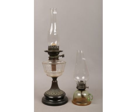 A Victorian brass based oil lamp raised on a black glass plinth with ribbed clear glass font and chimney along with a clear g