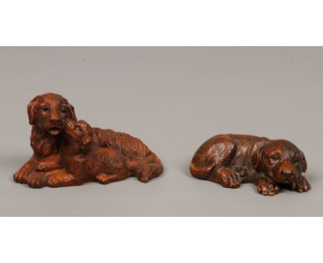 A carved hardwood model of a recumbent retriever and puppy with glass eyes, along with a similar canine carving.