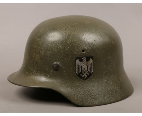 A German steel WWII Third Reich combat helmet. With national eagle and tri colour flag decals, the decals may have been appli