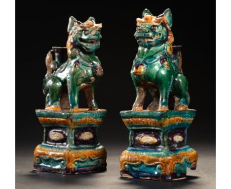 A PAIR OF CHINESE TILE WORKS GREEN AND OCHRE LEAD GLAZED MODELS OF BUDDHISTIC LIONS, MING DYNASTY, FIRST HALF 17TH C 19cm h +