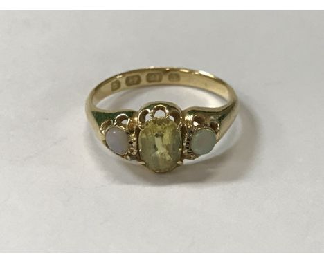 An 18 carat gold yellow sapphire and opal ring, the centre stone approx 0.75 carat, size N