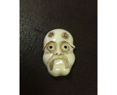 An unusual carved bone face netsuke with design on the reverse.