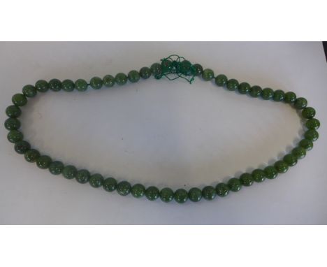 A green jade necklace, approx 64cm long, each bead approx 1cm wide, generally good 