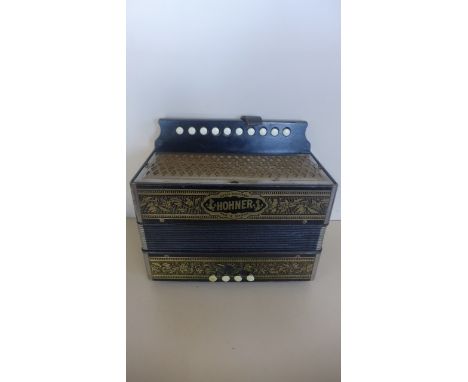 A Vintage Hohner accordion with four brass and ten buttons in playable condition with replacement side strap 