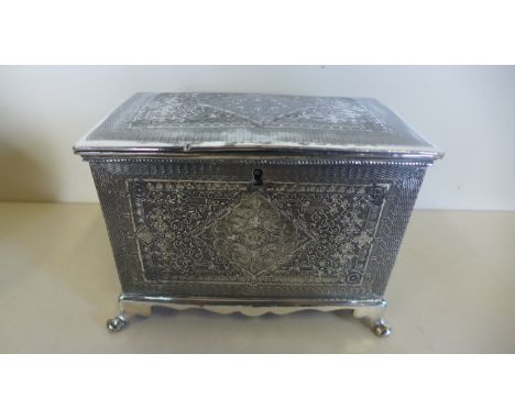 A silver plated tea caddy with fine eastern style decorated panels raised upon four feet, approx 11cm wide,12cm high, 10.5cm 