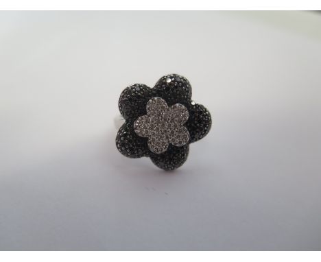 An 18ct white and black diamond daisy ring, sey in white gold, 20mm wide, size L/M approx 6.8 grams, in good condition 