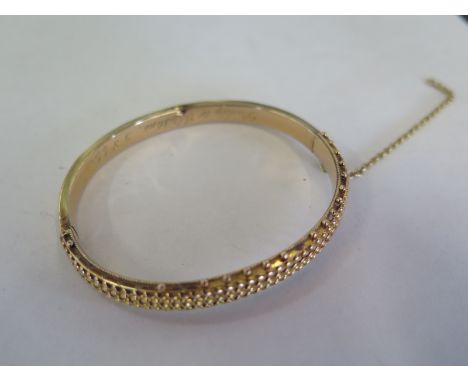 A gilt metal bangle engraved and dated 5.8.44 - 6.5 x 6cm - approx 9.6 grams, safety chain broken and some small dents, other