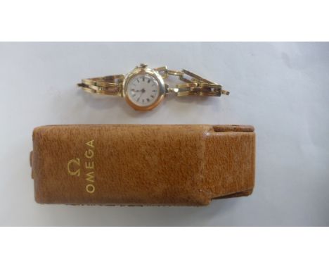 A 9ct yellow gold manual wind wristwatch on a spring strap, 27mm wide not working, approx 22 grams in an Omega box 