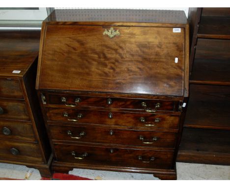 An early 19th Century mahogany bureau of small proportions, the plain top above a sloping fall front enclosing a fitted inter
